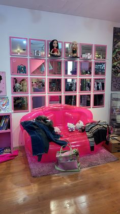 a pink couch sitting on top of a hard wood floor next to a book shelf