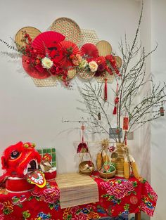 a red table topped with lots of decorations next to a vase filled with flowers and plants