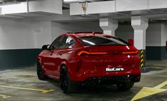 the rear end of a red car parked in a parking garage with yellow lines on the floor