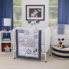 a mickey mouse crib bedding set in a child's room with blue curtains