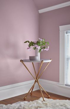 a vase with flowers sitting on top of a small table in front of a window