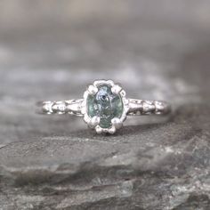 a close up of a ring with a green stone in the center on a rock