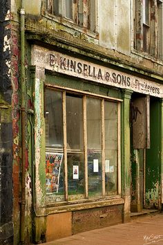 an old building with peeling paint and broken windows on the side of it's street