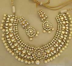 an elaborate necklace and earring set with pearls on the bottom, along with other jewelry pieces