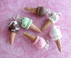 four ice cream cones are sitting on a pink tablecloth and one has a keychain