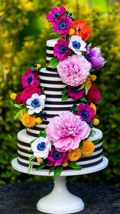 a multi - tiered cake with flowers on top is decorated in black and white stripes