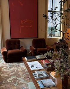 a living room with two chairs and a coffee table in front of a large painting