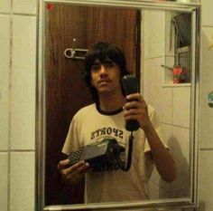 a man taking a selfie in front of a mirror holding a cell phone and a camera