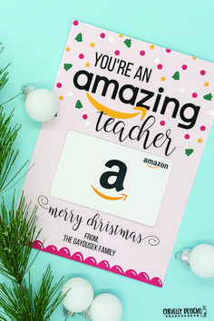 an amazon gift card sitting on top of a table next to christmas ornaments and pine branches