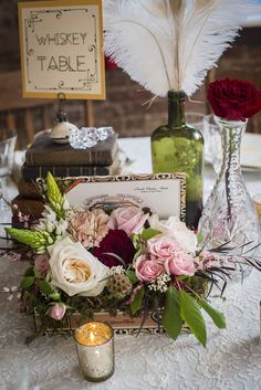 a table topped with flowers and candles next to a card holder filled with cards on top of a table