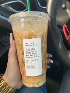 a person holding up a cup with noodles in it while sitting in the drivers seat