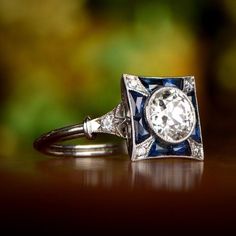 a diamond and sapphire ring sitting on top of a wooden table