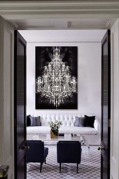 a living room filled with furniture and a chandelier hanging over the doorways