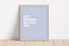 a framed poster with the words fifty reasons we love you in white on a light blue background