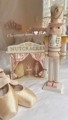 a nutcracker figurine next to a pair of ballet shoes on a bed