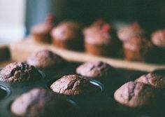 chocolate muffins sitting on top of a baking tray next to other muffins