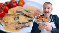 a man holding a plate with some food on it and tomatoes in the bowl next to him