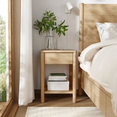 a bedroom with a bed, nightstand and plants on the side table next to it