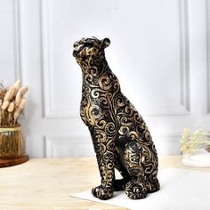 a black and gold bear figurine sitting on top of a table next to a vase