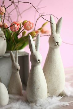 three white rabbits sitting next to each other on a fur covered floor with flowers in the background