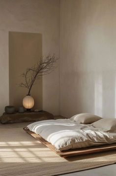 a bed sitting in the middle of a room next to a vase on top of a table