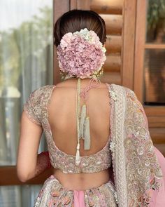 the back of a woman's dress with flowers in her hair and an elaborate necklace