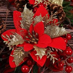 a red and gold christmas decoration with pine cones, holly berry berries and glittered leaves