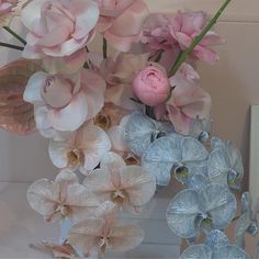 a vase filled with pink and white flowers on top of a table next to a mirror