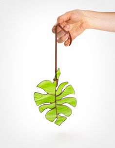 a hand holding a fake green leaf on a white background