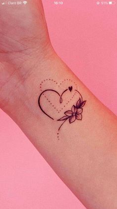 a small tattoo on the wrist of a woman with a heart and flower in it