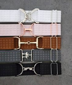 four different colored belts with metal buckles on each one and two pairs of glasses attached to them