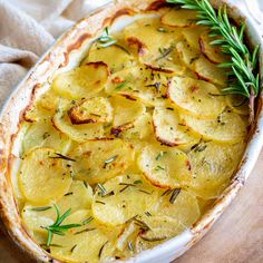 a casserole dish with potatoes and rosemary garnish