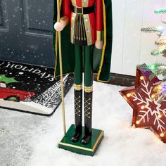 a nutcracker is standing in the snow next to a christmas tree and presents