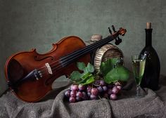 a violin, wine glass and grapes on a table