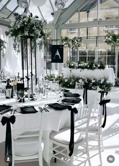 a table set up with black and white place settings for an elegant wedding reception in a greenhouse