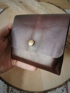 a person holding a brown wallet with a button on it