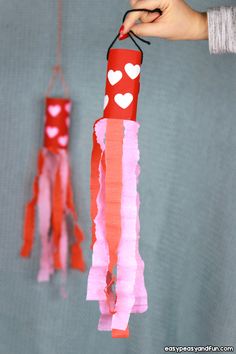 someone is holding up some red and pink paper with hearts hanging from the string on it