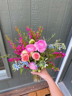 a person holding a bouquet of flowers in front of a door