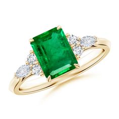 an emerald and diamond ring with three diamonds on the band, set in yellow gold