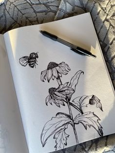 a drawing of a sunflower with two bees on it next to a fountain pen