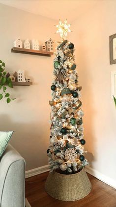 a decorated christmas tree in a living room with white and green ornaments on the top