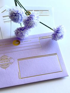 purple flowers are placed on top of an envelope