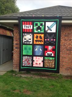 a quilt hanging on the side of a brick building in front of a garage door