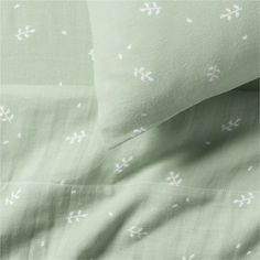 the sheets and pillow cases are green with white crosses on them, as well as two pillows