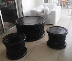 three black tables sitting on top of a tiled floor next to a white couch and chair