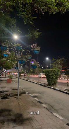 an empty street at night with lots of lights on the poles and trees in the background