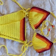 two pieces of crocheted swimsuit laying on top of a white sheet next to each other