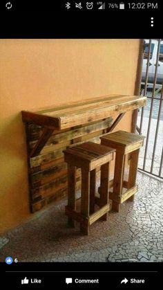 a wooden bench sitting next to a wall with two stools on top of it