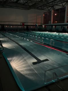 an empty swimming pool at night with the lights on and no one in it yet