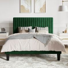 a green headboard on a bed in a white room with two pictures above it